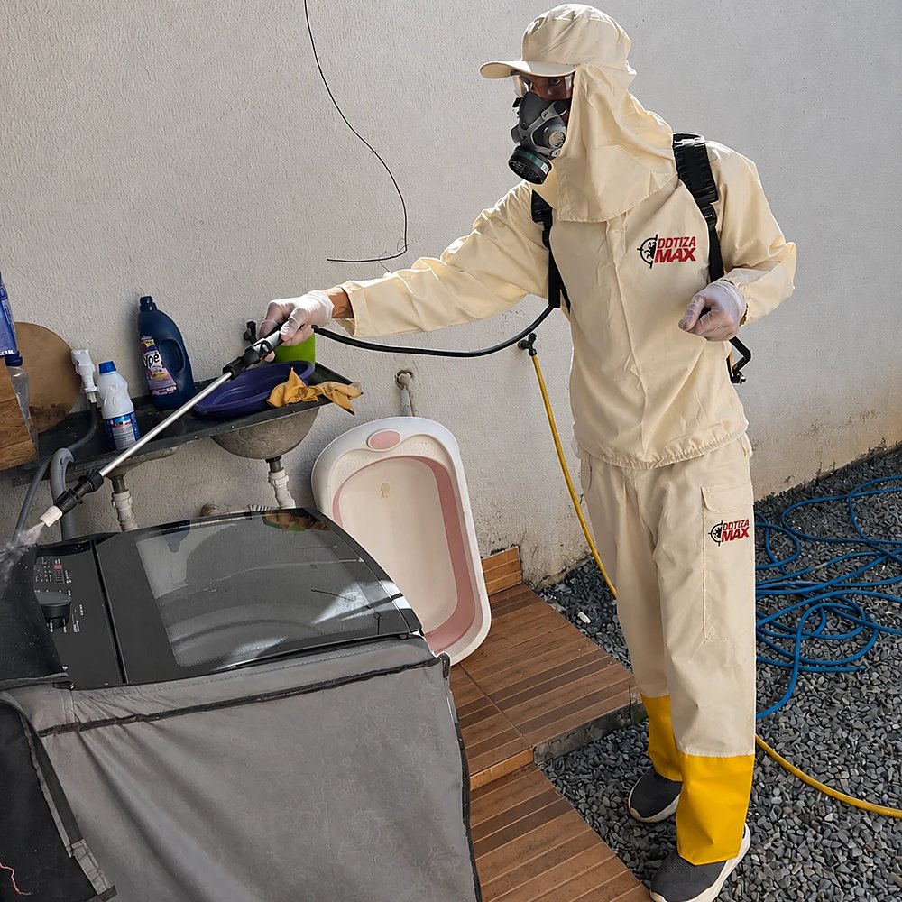Técnico da DDTizaMax, de uniforme e máscara, aplicando o tratamento na área de serviço de uma residência